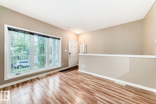 Expansive multi-pane window with white trim, wood-finish flooring, and a neutral color palette - 4 11917 103 Street, Edmonton, AB 