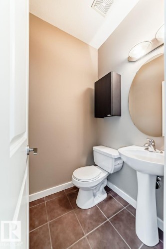 Powder room featuring a pedestal sink, a wall-mounted mirror, and tile flooring - 4 11917 103 Street, Edmonton, AB 