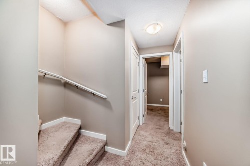 Carpeted staircase with white handrail and baseboards - 4 11917 103 Street, Edmonton, AB 