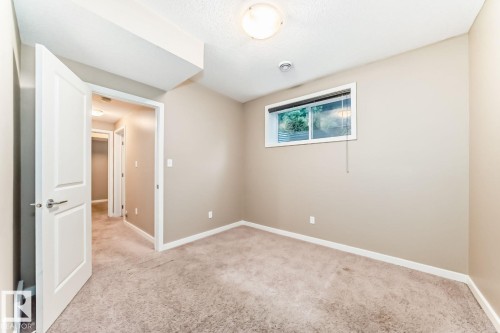 Carpeted room with neutral-toned walls, white trim, and a horizontal window featuring blinds - 4 11917 103 Street, Edmonton, AB 