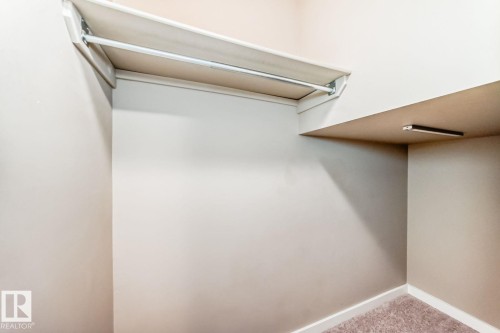 Recessed storage area featuring a built-in rod, upper shelf, and additional shelving with integrated lighting - 4 11917 103 Street, Edmonton, AB 