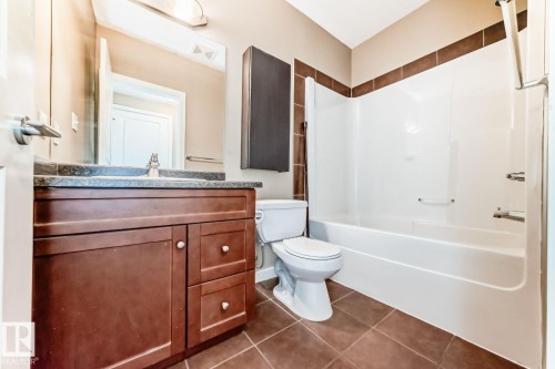 Brown floor tiles complement the vanity with a dark countertop and undermount sink - 4 11917 103 Street, Edmonton, AB 