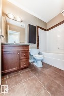 Bathroom featuring a wood-finish vanity with a dark countertop, an integrated sink, and a large wall mirror - 