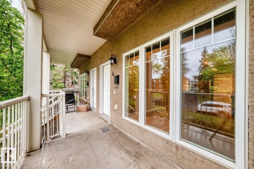 Private patio featuring a concrete surface, white spindle railing, and a textured stucco exterior - 4 11917 103 Street, Edmonton, AB 