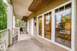 Private patio featuring a concrete surface, white spindle railing, and a textured stucco exterior - 