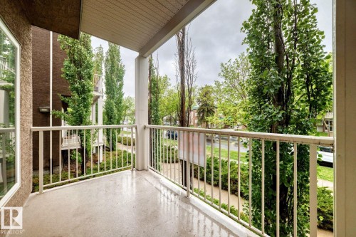 Private balcony featuring a painted concrete floor, white metal railing, and a textured stucco exterior - 4 11917 103 Street, Edmonton, AB 