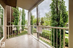 Private balcony featuring a painted concrete floor, white metal railing, and a textured stucco exterior - 