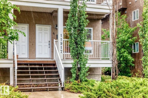 Multi-story building featuring a stucco exterior and multiple white panel doors - 4 11917 103 Street, Edmonton, AB 