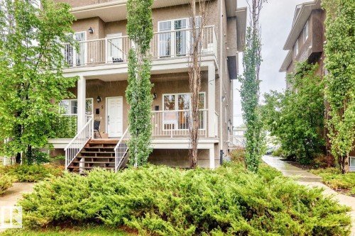 Multi-level stucco exterior featuring white trim, multiple balconies with white railings, and mature landscaping - 4 11917 103 Street, Edmonton, AB 