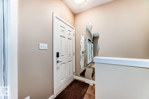 Entryway featuring a paneled door with smart lock hardware, neutral wall paint, and tiled flooring - 4 11917 103 Street, Edmonton, AB 