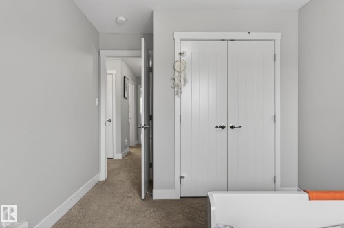 Interior hallway with light gray walls, white trim, paneled interior doors, and carpet flooring - 33 Durrand Bend, Fort Saskatchewan, AB 