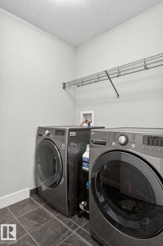 Laundry area featuring dark tile flooring, white baseboards, and a wire shelving unit - 33 Durrand Bend, Fort Saskatchewan, AB 