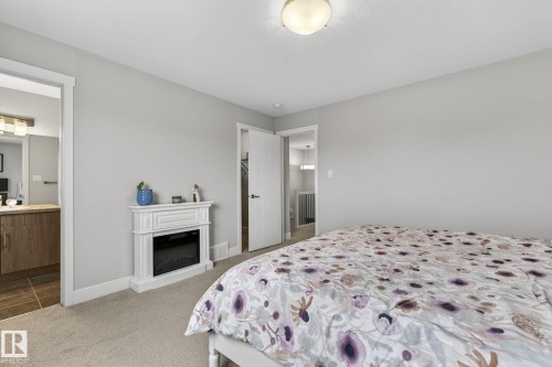 Light grey wall paint with white trim, featuring a built-in electric fireplace and plush carpet flooring - 33 Durrand Bend, Fort Saskatchewan, AB 