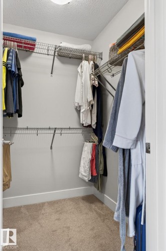 Walk-in closet featuring carpet flooring, crisp white baseboards, and a comprehensive wire shelving system - 33 Durrand Bend, Fort Saskatchewan, AB 