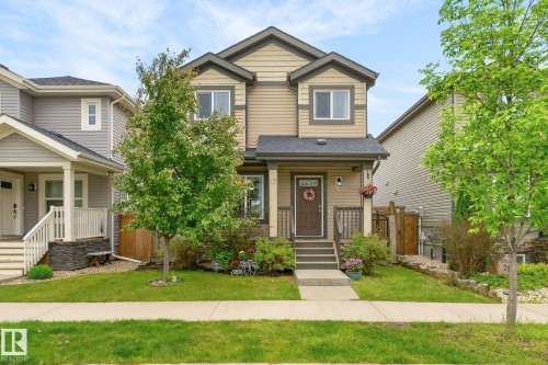 Two-story residence featuring a neutral-toned exterior with darker trim accents, a covered front entry, and a contrasting dark roof - 33 Durrand Bend, Fort Saskatchewan, AB 