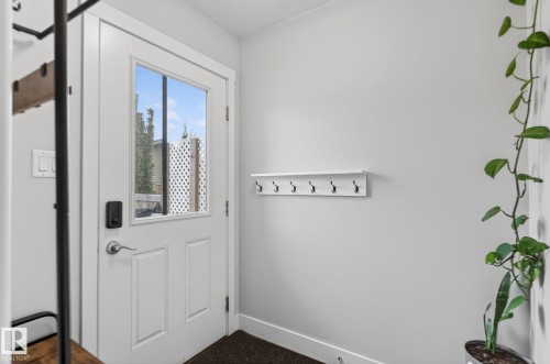 Entryway featuring a paneled door with glass insert, black smart lock hardware, and a wall-mounted coat rack - 33 Durrand Bend, Fort Saskatchewan, AB 