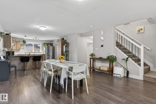 Open-concept living space featuring wood-finish flooring, a kitchen with stainless steel appliances, and a breakfast bar - 33 Durrand Bend, Fort Saskatchewan, AB 