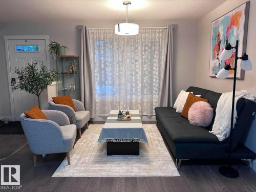 Spacious living area featuring wood-finish flooring, a white paneled entry door with frosted glass, and neutral wall paint - 33 Durrand Bend, Fort Saskatchewan, AB 
