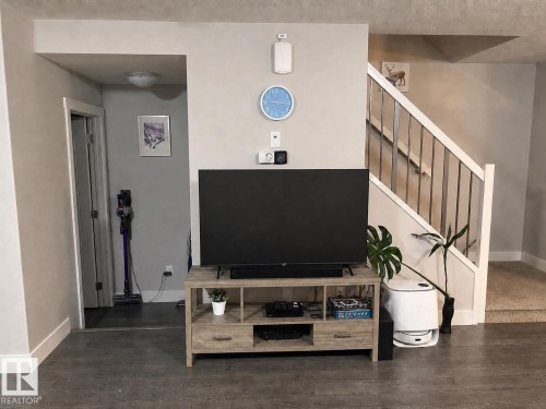 Open-concept living space with wood-finish flooring extending into a doorway - 33 Durrand Bend, Fort Saskatchewan, AB 