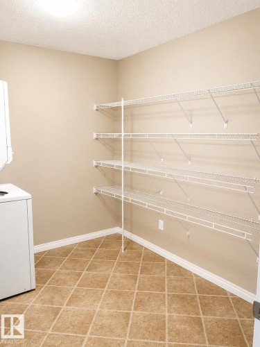 Utility room featuring extensive wire shelving, a tiled floor, and a neutral wall palette - 115 5340 199 Street, Edmonton, AB - Indoor With Storage