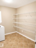 Utility room featuring extensive wire shelving, a tiled floor, and a neutral wall palette - 