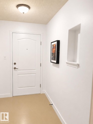 Entryway with a paneled door, flush-mount ceiling light, and wall niche with trim - 115 5340 199 Street, Edmonton, AB - Indoor Photo Showing Other Room
