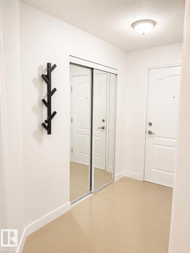 Entryway featuring a full-height mirrored closet with sliding doors, a flush-mount ceiling light fixture, and light-toned flooring - 115 5340 199 Street, Edmonton, AB - Indoor Photo Showing Other Room