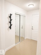 Entryway featuring a full-height mirrored closet with sliding doors, a flush-mount ceiling light fixture, and light-toned flooring - 