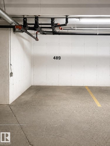 Designated parking space featuring concrete flooring, numbered demarcation, and overhead utility lines - 115 5340 199 Street, Edmonton, AB - Indoor Photo Showing Garage