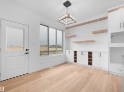Light wood-finish flooring complements custom white cabinetry with integrated shelving - 