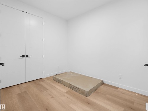 Light wood-finish flooring, white walls, and modern white doors with matte black hardware - 214 Crystal Creek Drive, Leduc, AB 