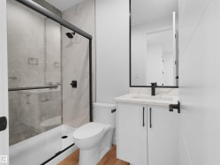 Contemporary bathroom featuring a white vanity with a marbled countertop, black framed mirror, and matte black fixtures - 