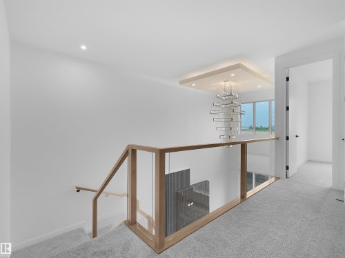 Upper-level landing featuring a modern chandelier, recessed lighting, and a contemporary glass and wood-finish railing - 214 Crystal Creek Drive, Leduc, AB 
