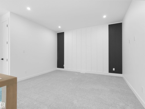 Room featuring light gray carpet, recessed lighting, and a white paneled accent wall with dark vertical slat details - 214 Crystal Creek Drive, Leduc, AB 