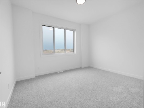 Neutral-toned room featuring a large window, light gray carpeting, crisp white walls, and a flush-mount ceiling light fixture - 214 Crystal Creek Drive, Leduc, AB 