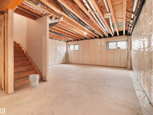 Unfinished basement space with concrete flooring, exposed wood joists, and two windows - 214 Crystal Creek Drive, Leduc, AB 