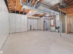 Unfinished basement with concrete flooring, insulated walls, exposed wood ceiling joists, and visible HVAC ductwork - 