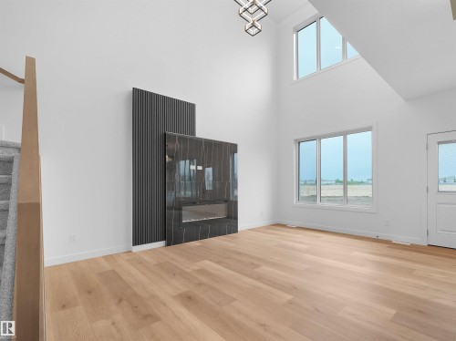 Spacious living area featuring high ceilings, wood-finish flooring, and ample natural light from multiple windows - 214 Crystal Creek Drive, Leduc, AB 