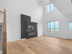 Spacious living area featuring high ceilings, wood-finish flooring, and ample natural light from multiple windows - 