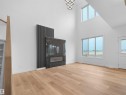Spacious living area featuring high ceilings, wood-finish flooring, and ample natural light from multiple windows - 214 Crystal Creek Drive, Leduc, AB 