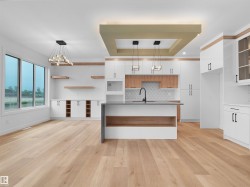 Open-concept kitchen and living area featuring wood-finish flooring, an expansive island with a waterfall countertop, and integrated appliances - 