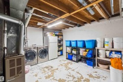 Utility space featuring exposed ceiling joists, concrete flooring, and a laundry area with appliances - 