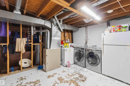 Utility room featuring exposed ceiling joists and ductwork, a washer and dryer, additional refrigeration, and a furnace unit - 203 11421 34 Street Nw, Edmonton, AB 
