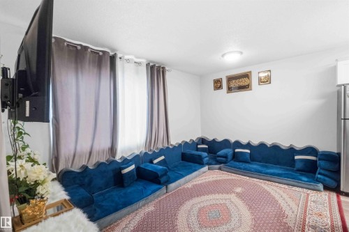 Spacious room featuring light-colored walls, a ceiling-mounted light fixture, and floor-length curtains - 203 11421 34 Street Nw, Edmonton, AB 