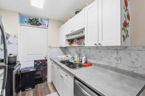 Kitchen featuring white shaker-style cabinetry, a double basin stainless steel sink, and a gray countertop - 203 11421 34 Street Nw, Edmonton, AB 