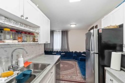 Galley-style kitchen featuring white cabinetry, a stainless steel sink with a high-arc faucet, and light-toned countertops - 