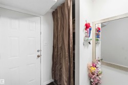 White paneled door with brass-toned hardware, complemented by a textured ceiling and a full-length mirror with a light-toned frame - 