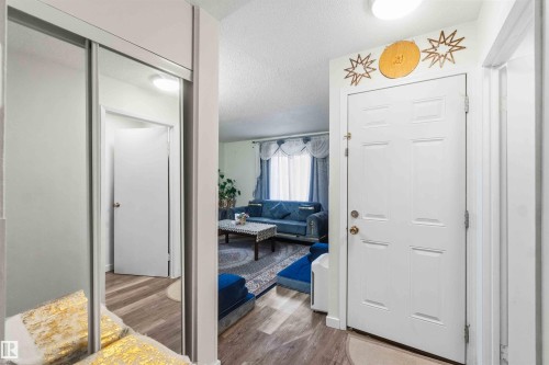 Entryway featuring wood-finish flooring and a full-length mirrored closet door - 203 11421 34 Street Nw, Edmonton, AB 