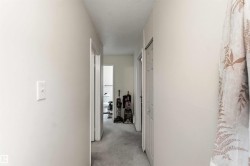 Interior hallway featuring light-colored walls and grey carpeting - 