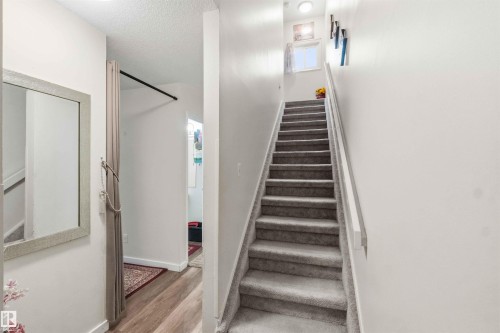 Carpeted staircase with white handrail ascending to an upper level - 203 11421 34 Street Nw, Edmonton, AB 